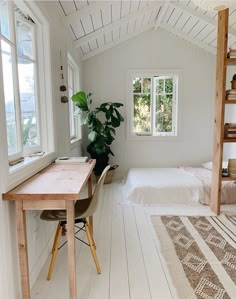 a bedroom with white walls and wood flooring next to a bed in a loft