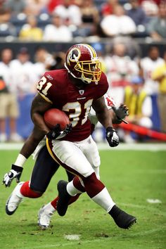 a football player running with the ball in his hand and people watching from the stands