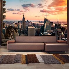 a couch sitting in front of a large cityscape with the sun setting behind it