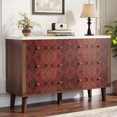 a wooden dresser sitting on top of a hard wood floor next to a lamp and potted plant