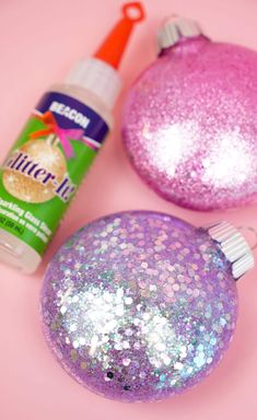 two glitter ornaments are sitting on a pink surface