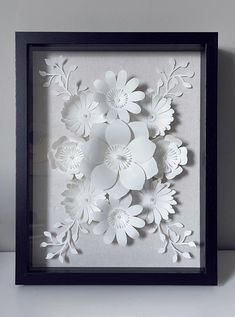 paper flowers in a black frame on a table