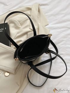 a black purse sitting on top of a white bed