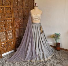 Made to Order/Measurement/Custom Order Lehenga - Color : Grey - Fabric : Art Silk - Flared (8m) Paneled Lehenga skirt with Mirror Border - Beige Brocade Spaghetti Blouse - Grey Net dupatta with Border - Drawstring closure with designer latkan - Can can attached PLEASE NOTE: BUYERS ARE RESPONSIBLE FOR ANY CUSTOMS AND IMPORT TAXES THAT MAY APPLY. Fabric Care : Dry Clean Only Disclaimer: Please note the photographs are taken by mobile camera in sunlight The actual color of the product might slightly differ due to exposure of light or monitor's display Shipping: This is made to order product. We customize the pattern of the dress to suit your style and fitting. Once you place the order we will provide you with a template for measurements (to be taken in inches). It usually takes a week's time Designer Brocade Lehenga With Gota Work, Brocade Lehenga With Gota Work For Designer Wear, Floor-length Silk Choli With Gota Work, Silk Choli With Self Design For Reception, Brocade Sets With Gota Work In Traditional Drape, Silk Self-design Choli For Reception, Silk Reception Choli With Self Design, Traditional Silk Gown With Unstitched Blouse, Silk Lehenga With Self Design For Reception