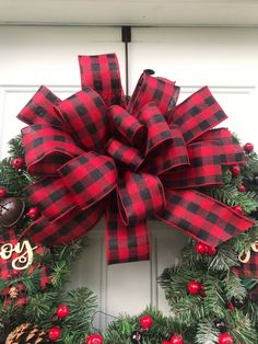 a red and black plaid christmas wreath hanging on a door