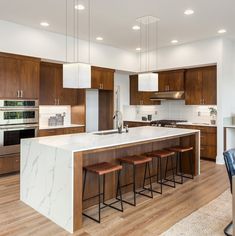 a large kitchen with wooden cabinets and white counter tops, along with bar stools