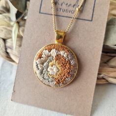 a gold necklace with an embroidered flower on it