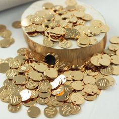 a pile of gold coins sitting on top of a white table next to a box