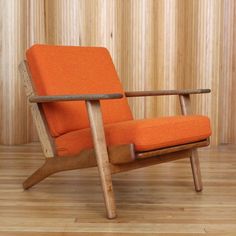 an orange chair sitting on top of a hard wood floor next to a wooden wall