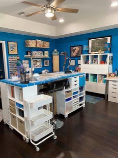 a room with blue walls and lots of white drawers on the desk, along with many other items