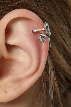 a close up of a person's ear with a small silver frog on it