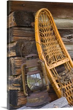 an old chair and lantern sitting on top of a pile of books next to a wooden wall