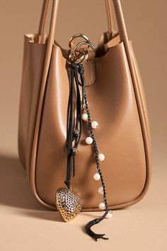 a handbag with a tassel hanging from it's side and a keychain attached to the handle