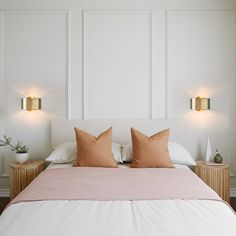 a bed with two lamps on either side of the headboard and pillows on it