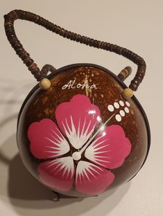 a pink and white flower on top of a brown ball with beaded handles is hanging from a hook