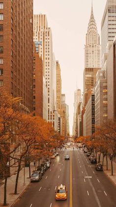 an empty city street with cars parked on the side and tall buildings in the background