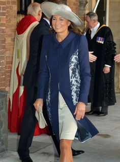 a woman in a blue coat and hat is walking down the street with other people