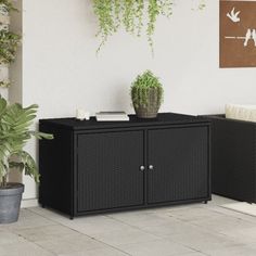 an outdoor living area with two black wicker cabinets and potted plants on the floor