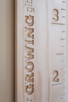 a wooden ruler with the word growing on it's side next to a wall