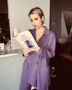 a woman in a purple suit holding a book