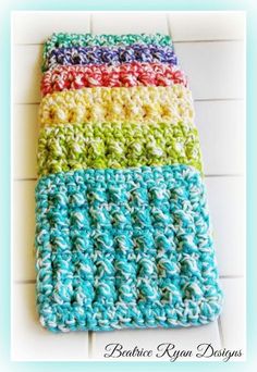 the crocheted dishcloth is multicolored and sits on a tile floor