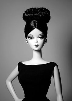 a black and white photo of a barbie doll wearing a dress with a high bun