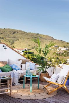 an outdoor living area with chairs, tables and plants on the roof terrace overlooking mountains