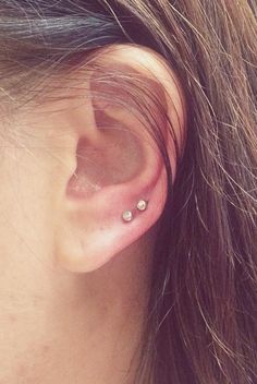 a close up of a person's ear with two small studs on it