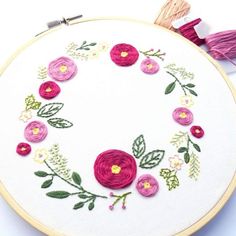 a close up of a embroidery on a white surface with pink and yellow flowers in the center