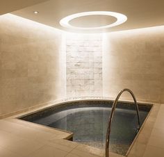 an indoor jacuzzi is lit up in the middle of a room with stone walls and flooring