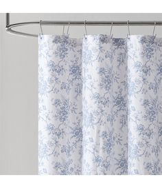 a shower curtain with blue and white floral print on the outside, hanging from a metal rod