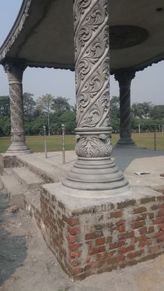 an old stone pillar in the middle of a park with two pillars on each side