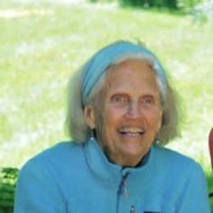 an older woman sitting in front of a tree with a frisbee on her lap