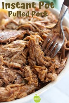 a white bowl filled with pulled pork next to a fork