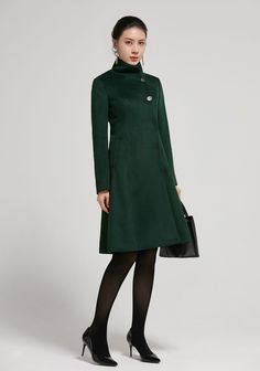 "Elegant fit and flare coat by Xiaolizi. Lovely detail with the buttons and twin waist pockets. Stand up collar and fully inside lined. Made in soft dark green wool fabric. DETAIL * 50% wool blend, 50% fiber,nylon * fully satiny lining, more nice to the touch body * stand collar * Long sleeve * Two seam big pockets that can slide your whole hands in it * single breasted front with button and snap closure * A Line coat, vintage wool coat * above knee length * Lean More about the items From the FA Solid A-line Outerwear For Fall, Fall Knee-length Single-breasted Outerwear, Winter Wool Coat For Office, Knee-length Single Breasted Winter Outerwear, Knee-length Outerwear With Button Closure For Winter, Winter Knee-length Outerwear With Button Closure, Fitted Long Wool Coat In Solid Color, Solid A-line Outerwear For Work, Wool Coat With Button Closure And Stand Collar