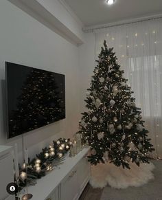 a decorated christmas tree in the corner of a living room with white lights and decorations