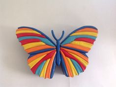 a multicolored butterfly brooch sitting on top of a white table next to a wall