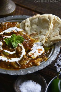 a plate with some food on top of it next to pita bread and green peppers