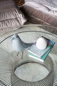 a glass table with two birds on top of it and a book in the middle