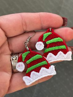 someone is holding two christmas themed items in their hand, one has a bell and the other has a pair of earrings