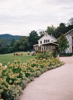 a house with flowers in front of it and a walkway leading to the back door