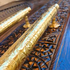 two gold colored fountain pens sitting on top of a wooden table next to each other