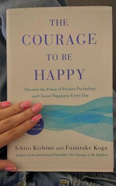 a woman holding a book in her hands with the title'the courage to be happy '