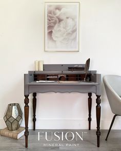 a grey desk with a white chair next to it and a painting on the wall