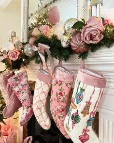 christmas stockings hanging from a mantel decorated with pink flowers