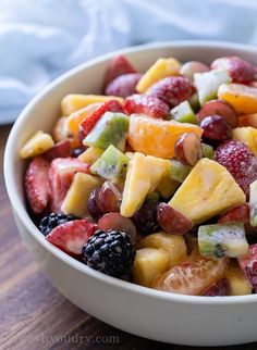 a white bowl filled with fruit salad on top of a wooden table