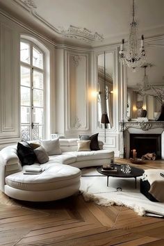 a living room filled with white furniture next to a fire place and a mirror on the wall