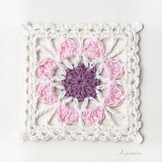 a crocheted square with pink and white flowers on it, in the shape of a flower