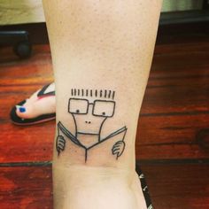 a person's foot with a tattoo on it that has a drawing of a man reading a book