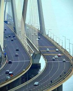 an aerial view of a bridge with cars driving on it's sides and the ocean in the background